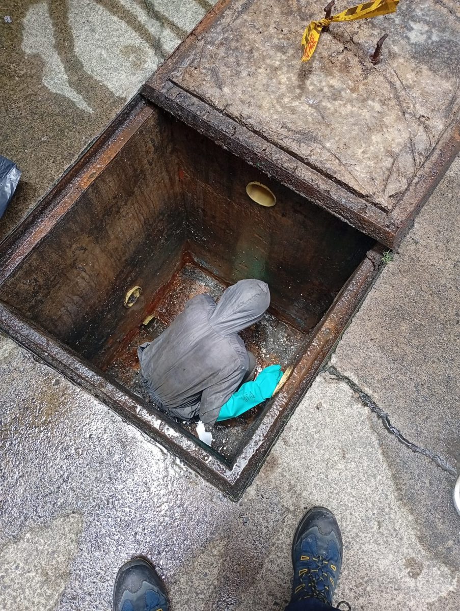 Operario limpiando el fondo de una caja de aguas servidas