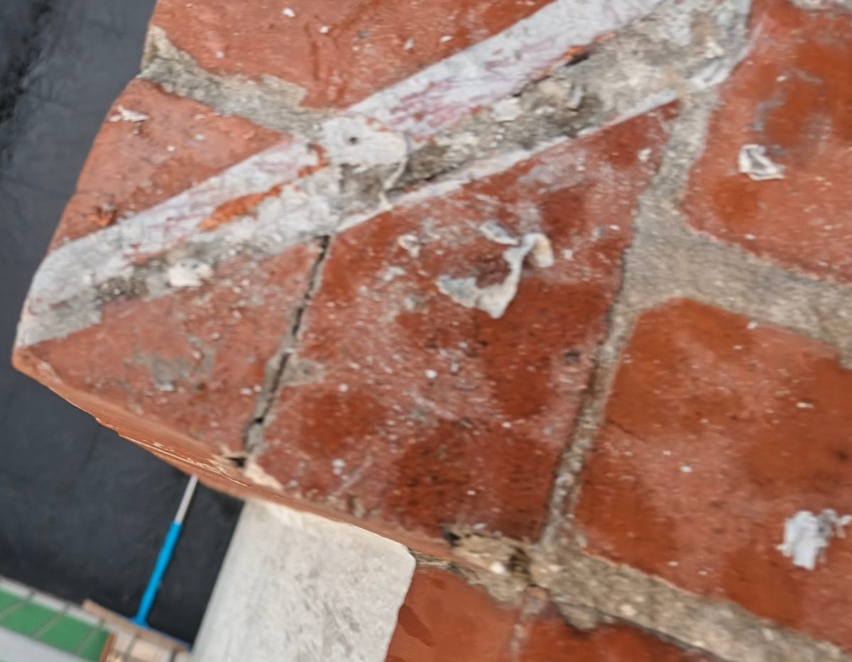 Antes: juntas de ladrillo fisuradas y desprendidas en el remate del muro